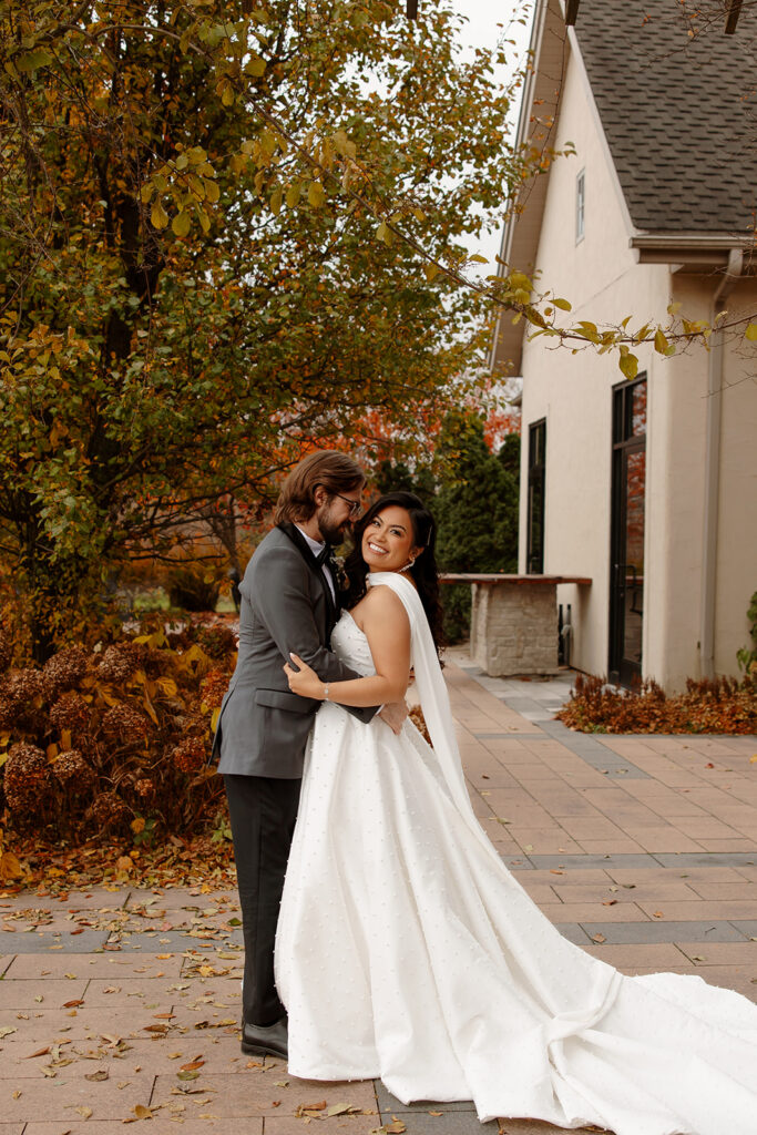 Mariah and Nathan pose together outside RiverStone, with the venue's stone exterior and architectural details framing their portrait.